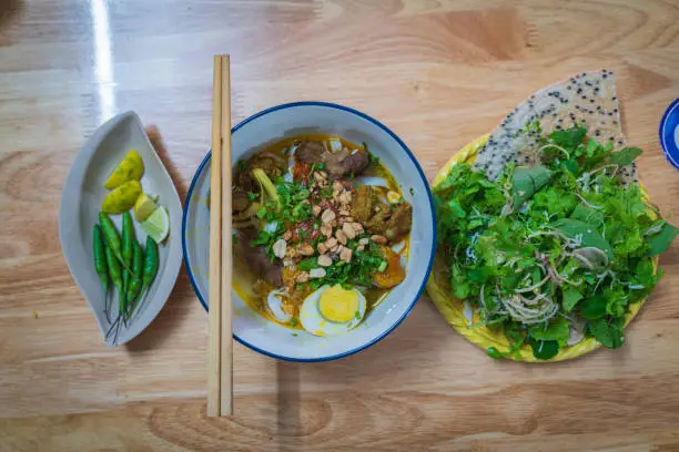 Traditional Mi Quang noodles served with fresh herbs and rice crackers in Da Nang