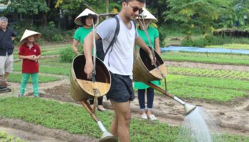 Guest carrying traditional watering buckets while farming in Da Nang