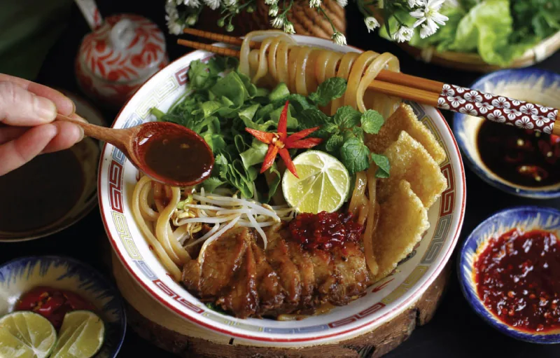 Cao Lau - thick noodles with smoky pork and fresh herbs, the signature dish of a Hoi An Food Tour